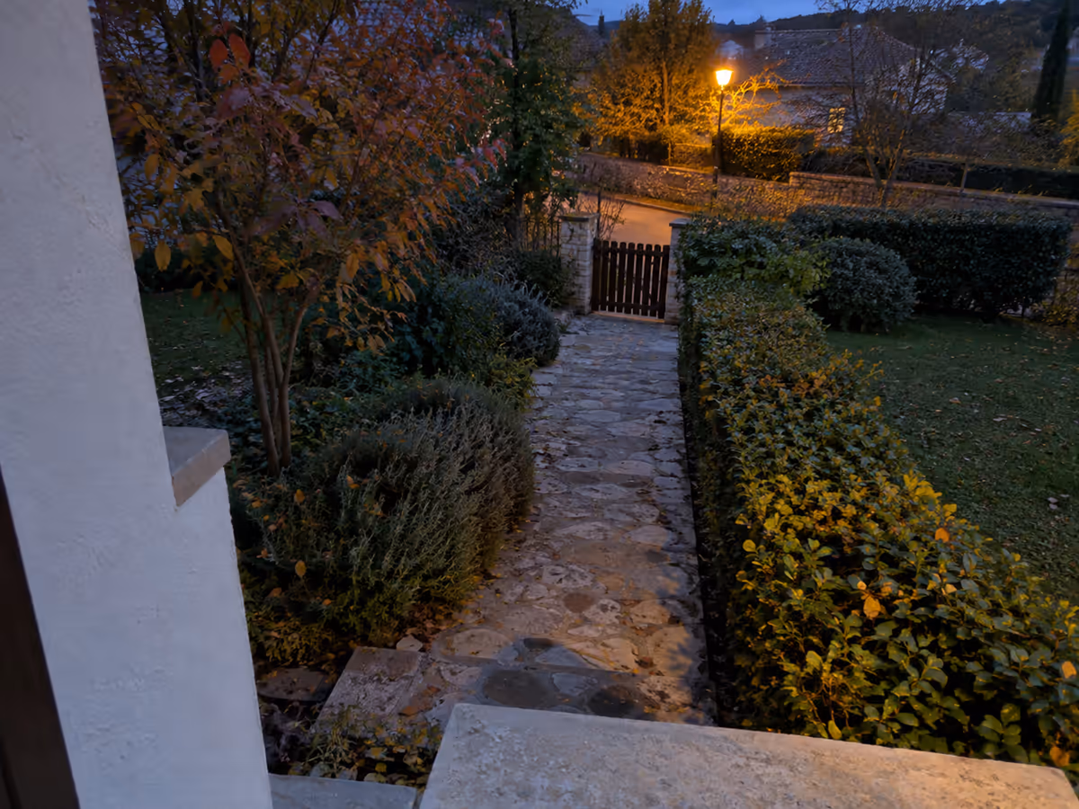 Vue en plongée depuis un mur au crépuscule, une allée pavée descendant vers un portail, le champ d'un détecteur de mouvement