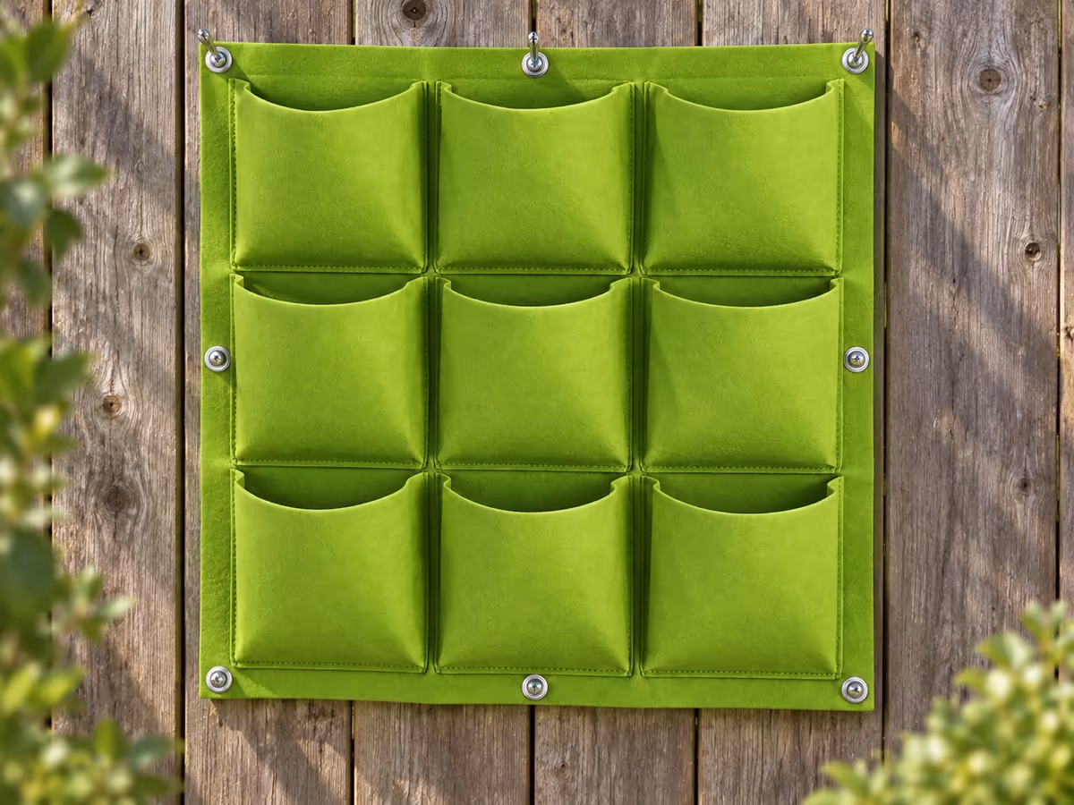 Huit vis à œil métalliques engagées dans les œillets d'un panneau de feutre vert clair tendu à plat sur un mur de clôture en bois