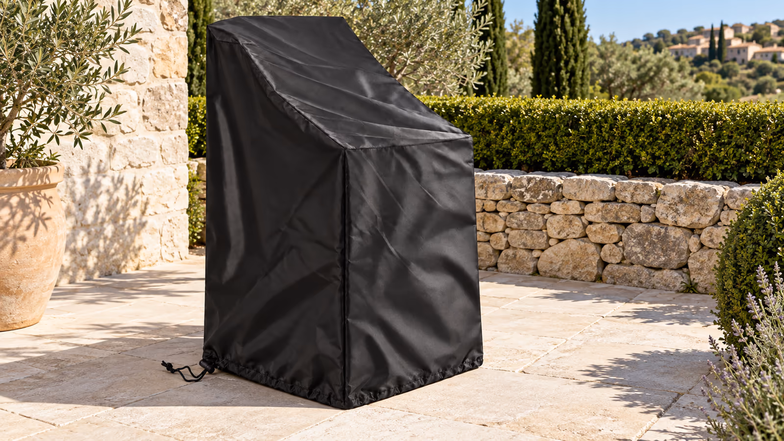 Housse de protection noire à cordon posée sur une pile de chaises de jardin empilables, terrasse dallée en plein soleil d'été