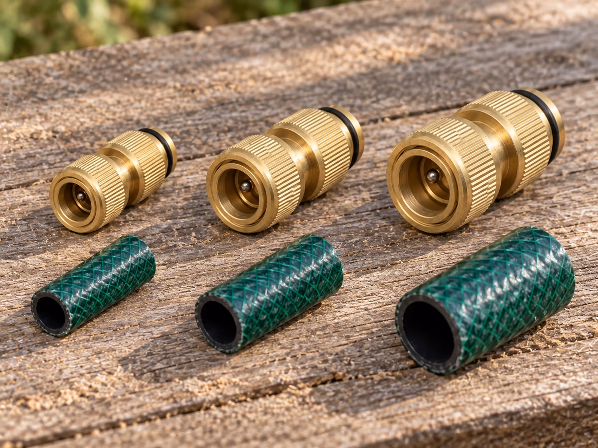 Trois raccords rapides en laiton de calibres différents alignés sur une planche de bois, à côté de trois tronçons de tuyau de diamètres croissants