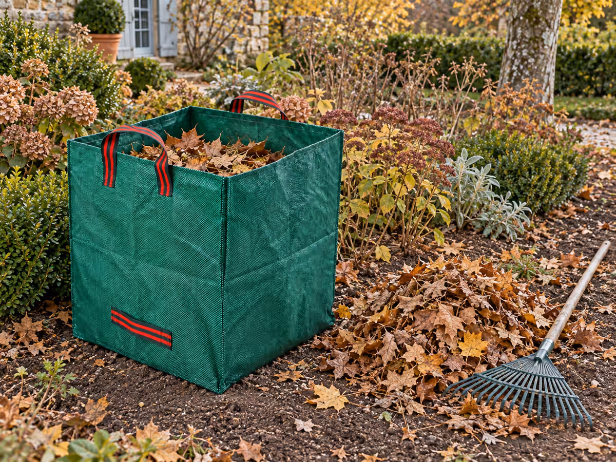 Sac de jardin pliable de 270 litres en toile tissée ouvert dans un massif, à côté d'un tas de feuilles mortes