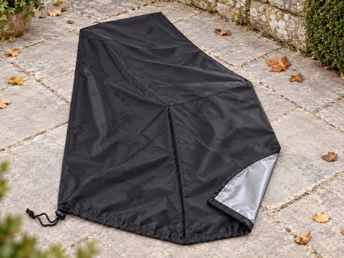 Housse de protection noire étalée à plat sur une terrasse pour sécher, enduit argenté visible sur la face interne retournée
